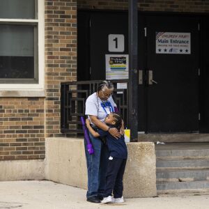 Cornell Moses Jr., 6, hugs a school employee while waiting for his mother at Genevieve Melody Public School in West Garfield Park.