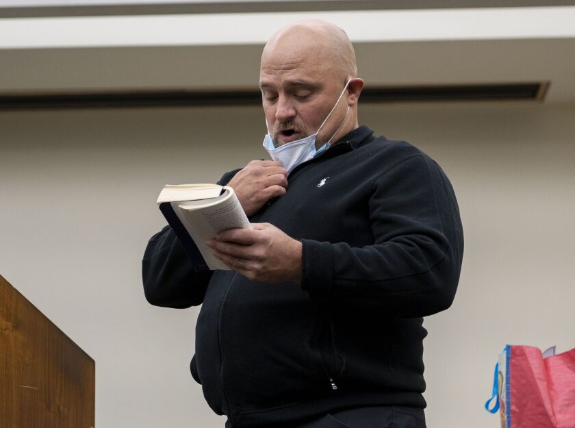 Nathan Moser, a Navy veteran, reads a passage from his Alcoholics Anonymous “Big Book” during a Veterans Court rehabilitation program graduation ceremony at the Skokie Courthouse in October 2021.