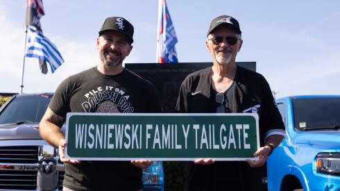 From left: Father and son White Sox fans John and Rich Wisniewski hold up a custom family tailgating sign outside Rate Field in Bridgeport on the South Side, Tuesday, Oct. 6, 2026.