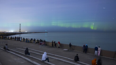 People watch the Northern Lights shine over Lake Michigan near Montrose Bird Sanctuary on Wednesday.