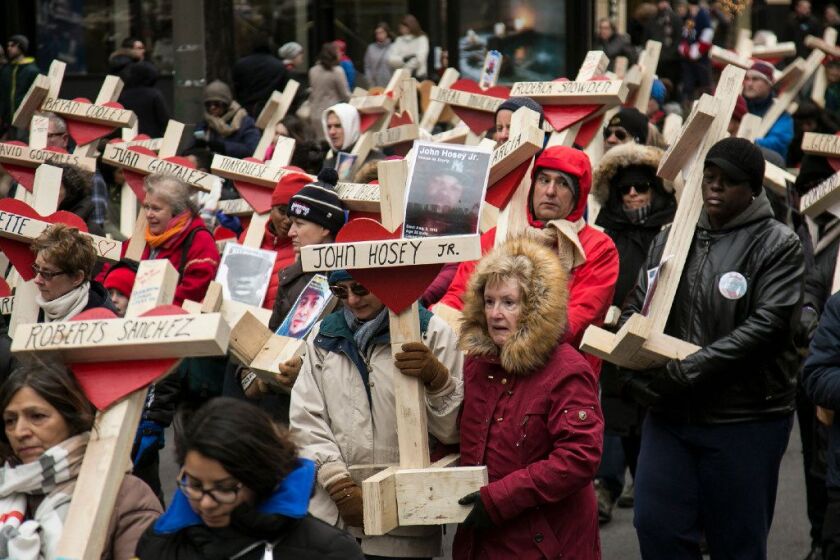 A cross bearing the name and photo of John Hosey Jr., one of the 16 people killed in Beat 1133 last year, was carried down Michigan Avenue in a march organized by the Rev. Michael Pfleger at the end of 2016. | Ashlee Rezin / Sun-Times