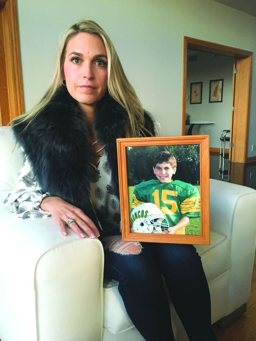 Lisa DiMucci holds a photo of her husband, Sal, when he was an 8-year-old on his youth football team. | RICK TELANDER/SUN-TIMES
