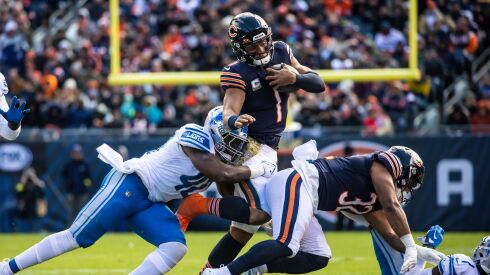 A photo of Bears quarterback Justin Fields running with the ball against the Lions.