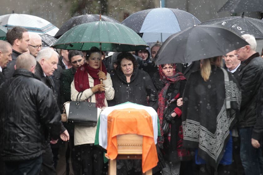 Bernie McGuinness (center) looks at the coffin of her husband Martin as she waits to bring his body back to their home in the bogside area of Derry/Londonderry, Northern Ireland, on Tuesday. | Peter Morrison/Associated Press