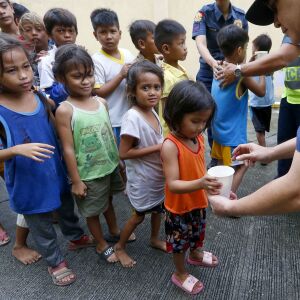 Manila police give out rice porridge to residents living along the coastal community of Baseco as they evacuate during the onslaught of Typhoon Mangkhut which barreled into northeastern Philippines before dawn Saturday, Sept. 15, 2018 in Manila, Philippin