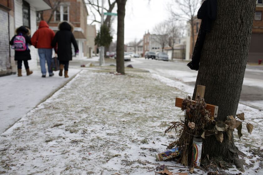 People walk past a makeshift memorial to someone who was killed. | Joshua Lott / The Trace