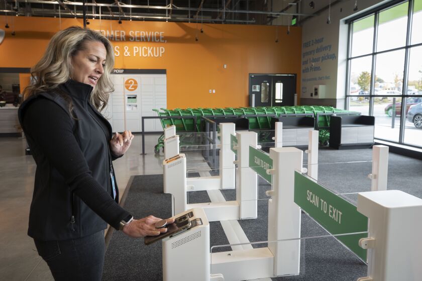 District Manager Martha Marinelli demonstrates the requirement to scan the phone app before exiting the new Amazon Fresh store in Westmont.