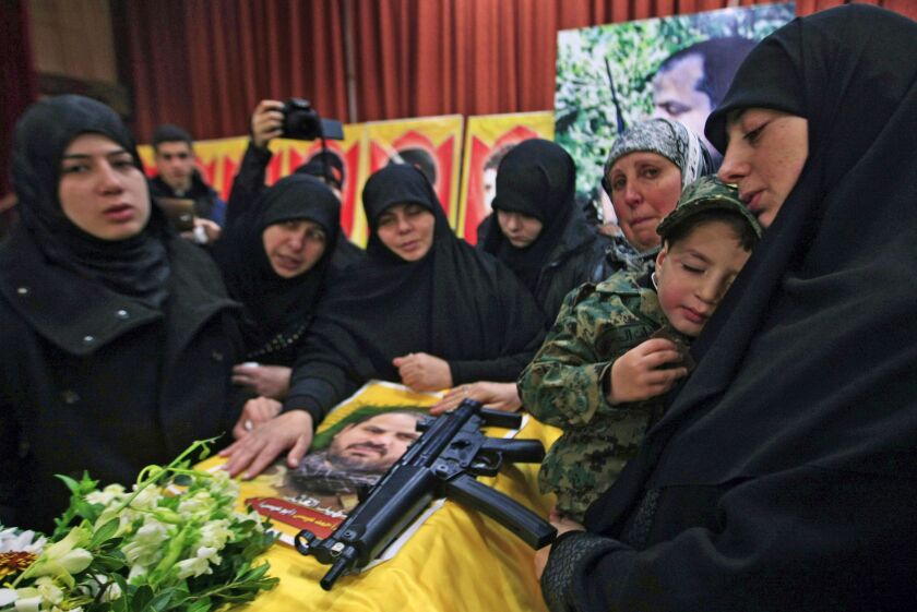 The sister of Hezbollah member Mohammad Issa who was killed in an Israeli airstrike in Syria on Sunday, holds his son Ahmed as she mourns over his coffin during his funeral procession, in the southern village of Arab Salim, Lebanon, Tuesday, Jan. 20, 201