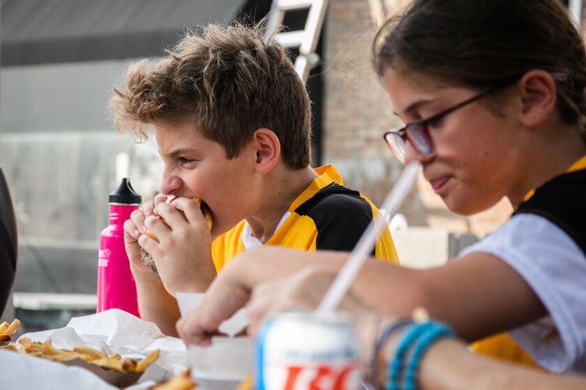 Joe Caldarone, 11, takes a bite from his burger at Big Guys Sausage Stand in Berwyn, Ill., Saturday, Sept. 17, 2022. The shop, which opened in 2012, is set to close its counter service “indefinitely” on September 24 and focus on providing catering services, according to their Facebook page.