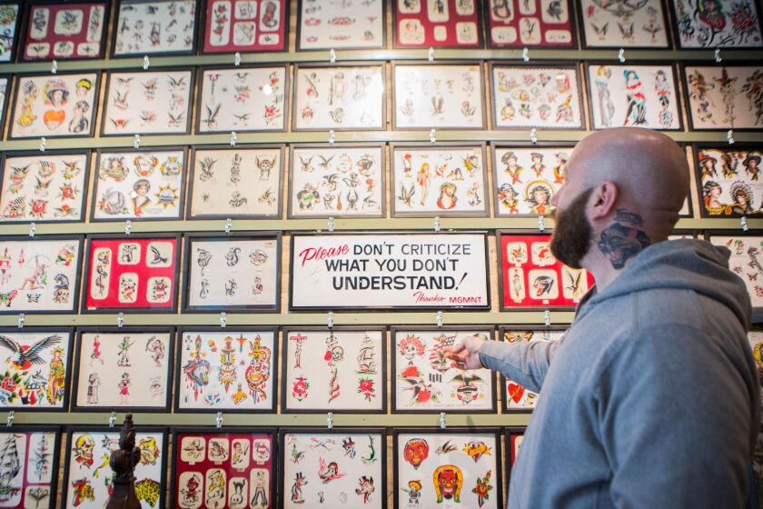 Nick Colella in front of a wall of vintage flash from the mid-20th century mixed in with contemporary images created by artists working at Great Lakes Tattoo in Chicago, Wednesday, March 9, 2016. Flash is the example of an image that the artist can make i